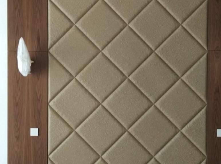 Parete di una camera rivestita con pannello a losanghe imbottite beige tra due fasce in legno noce