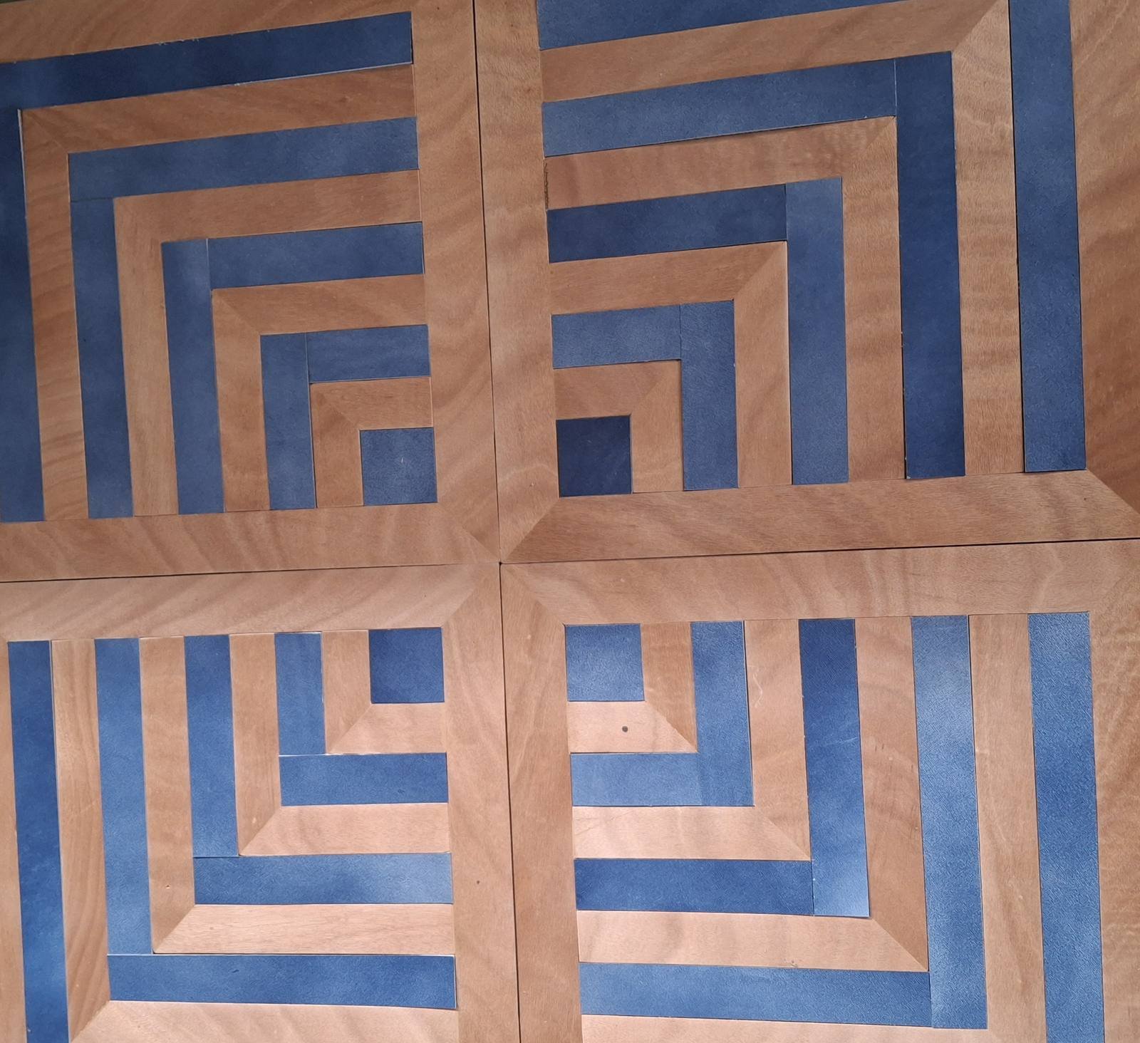 Quadrotte di pavimento con motivo a greca in legno chiaro e inserti in pelle blu concentrici